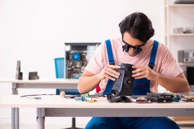 Genç bir erkek müteahhit bilgisayar tamir ediyor.
