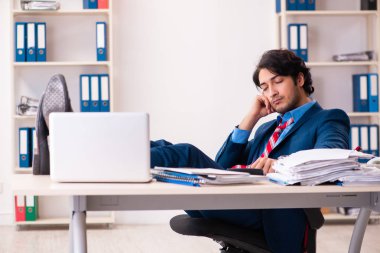 Genç yakışıklı işadamı ofiste oturuyor.