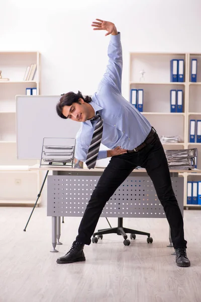 Jovem bonito masculino empregado fazendo exercícios no escritório — Fotografia de Stock