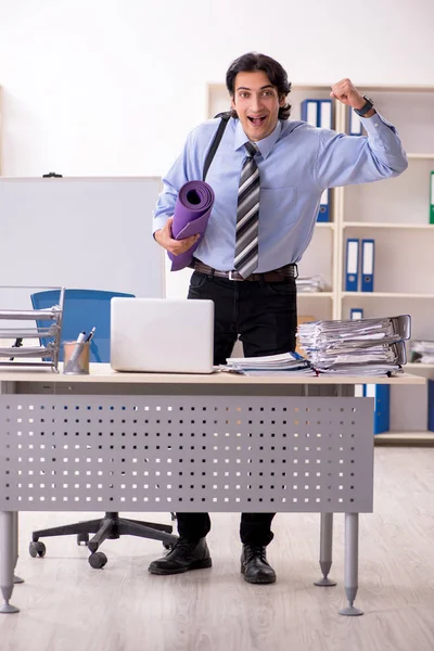 Young handsome male employee doing exercises in the office