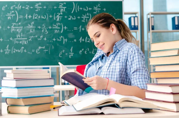 Siswa perempuan dengan banyak buku duduk di dalam kelas — Stok Foto