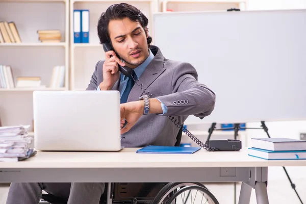 Jovem e bonito funcionário em cadeira de rodas no escritório — Fotografia de Stock