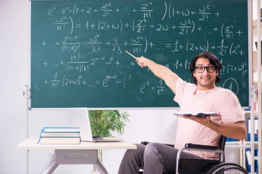 Yakışıklı delikanlı kara tahta önünde tekerlekli sandalyede