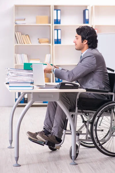 Young handsome employee in wheelchair at the office