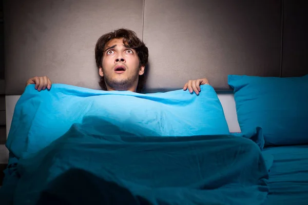 Fiatal férfi megijedt az ágyában rémálmok gyötörnek — Stock Fotó