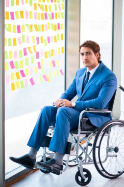 Birçok çelişkili önceliği olan tekerlekli sandalyedeki genç yakışıklı adam.