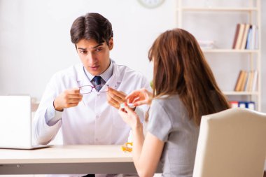 Genç bir kadın, erkek doktor göz doktorunu hastanede ziyaret ediyor.