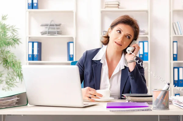 Middle-aged female employee sitting at the office