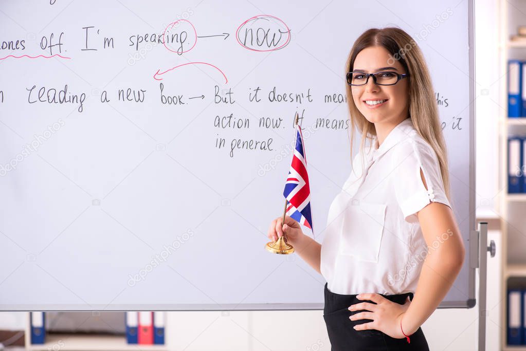 Young female english language teacher standing in front of the b