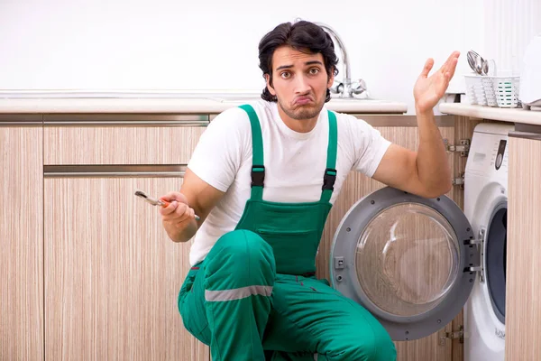 Joven contratista reparando lavadora en cocina — Foto de Stock