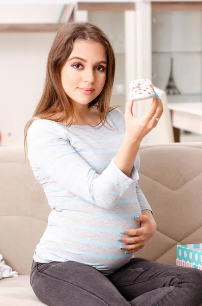 Młoda kobieta w ciąży, siedząc na kanapie w domu — Zdjęcie stockowe
