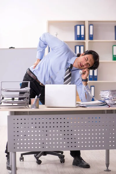 Young handsome male employee doing exercises in the office