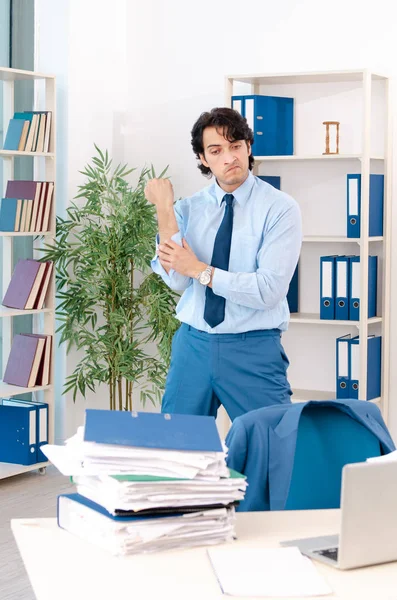 Giovane bel dipendente maschio con troppo lavoro in ufficio — Foto Stock