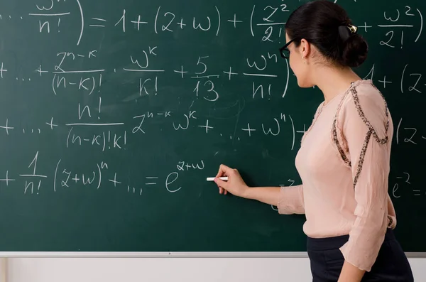 Female teacher standing in front of chalkboard — Stock Photo, Image