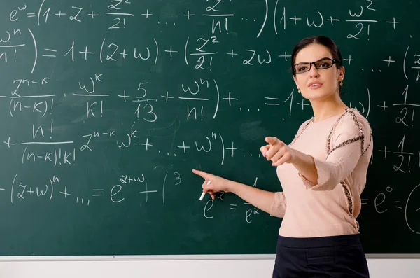 Female teacher standing in front of chalkboard — Stock Photo, Image