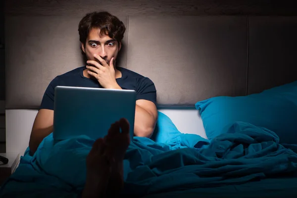 Man som arbetar på bärbara dator på natten i sängen — Stockfoto