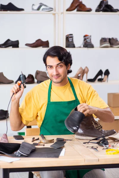 Ung man reparera skor i verkstad — Stockfoto