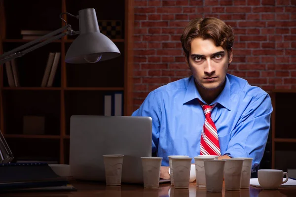 Ung anställd dricker kaffe och jobbar nattskift — Stockfoto