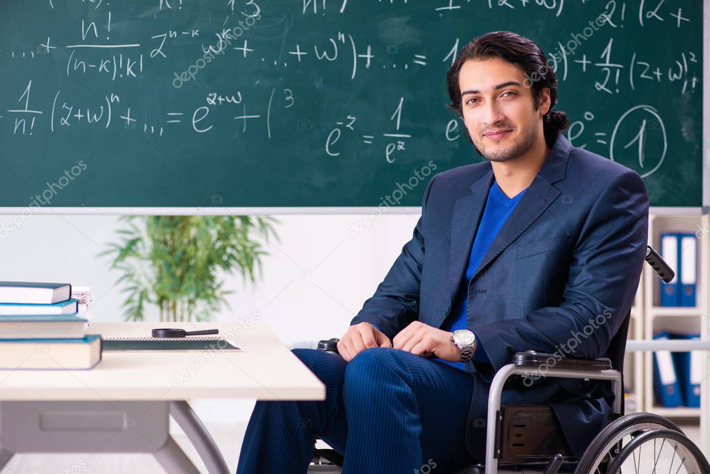 Young handsome man in wheelchair in front of chalkboard 