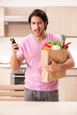 Yakışıklı delikanlı mutfakta sebze ile 