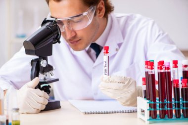 Genç yakışıklı laboratuvar asistanı hastanede kan örnekleri test ediyor. 