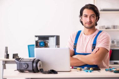 Genç bir erkek müteahhit bilgisayar tamir ediyor.  