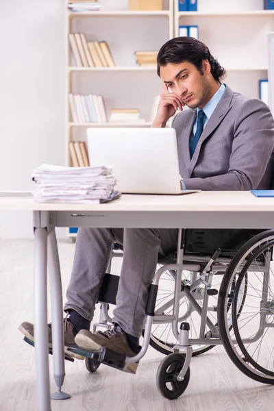 Jovem e bonito funcionário em cadeira de rodas no escritório — Fotografia de Stock