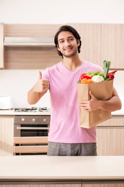 Fiatal jóképű férfi a konyhában zöldségekkel — Stock Fotó