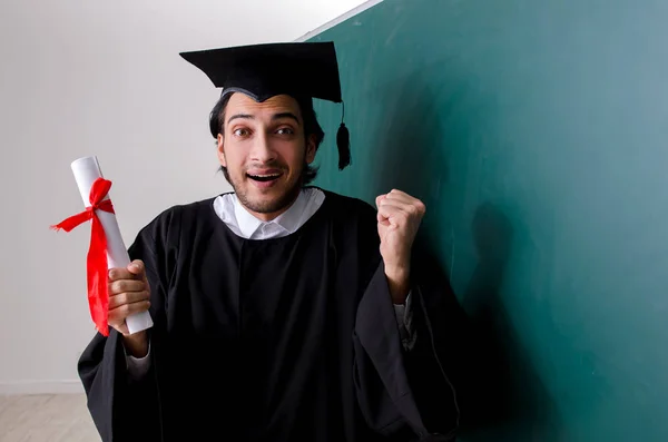 Estudante graduado na frente do quadro verde — Fotografia de Stock