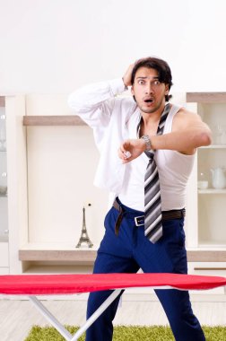 Genç adam yatak odasında ütü yapıyor.