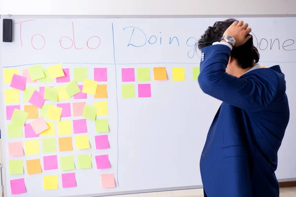 Young handsome employee in front of whiteboard with to-do list — Stock Photo, Image