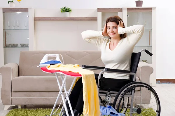 Femme en fauteuil roulant repassage à la maison — Photo