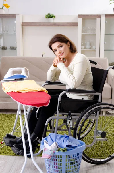 Donna in sedia a rotelle stiratura a casa — Foto Stock