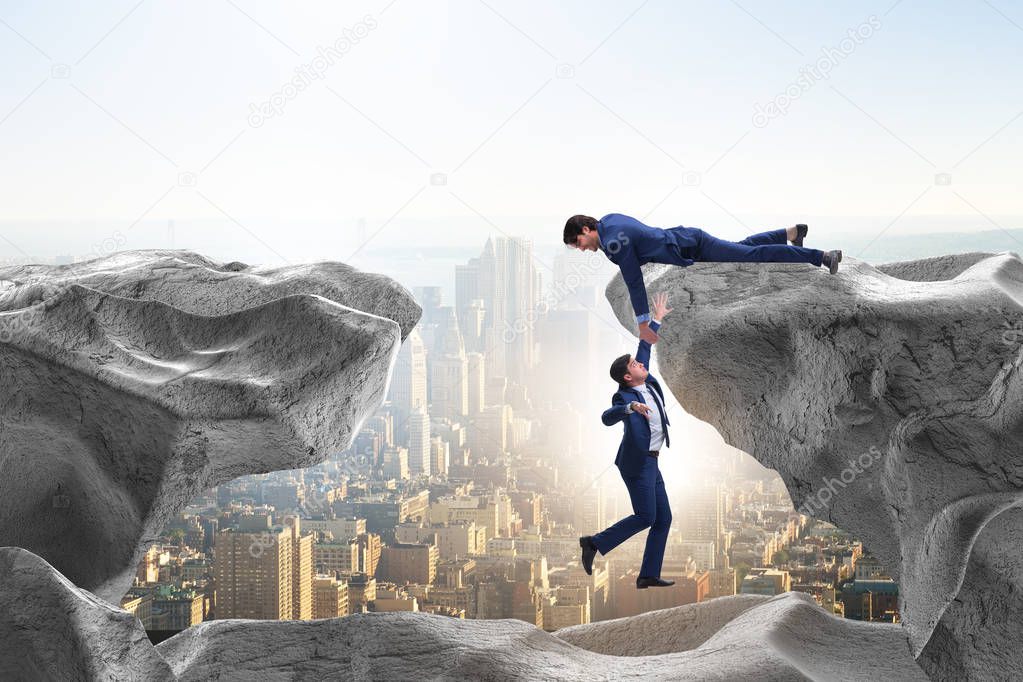 Businessman offering helping hand to falling colleague