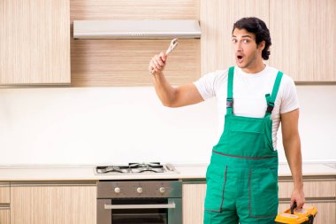 Genç müteahhit mutfakta fırın onarıyor. 