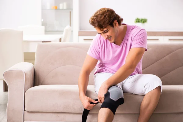 Joven con la rodilla lesionada recuperándose en casa —  Fotos de Stock