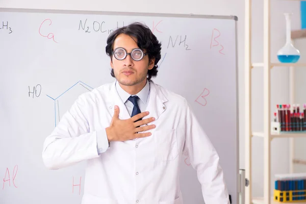 Mladý chemik legrační před bílou tabuli — Stock fotografie