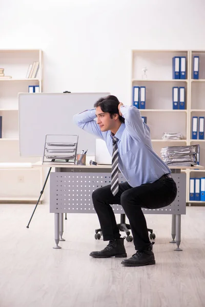 Giovane bel dipendente maschio che fa esercizi in ufficio — Foto Stock