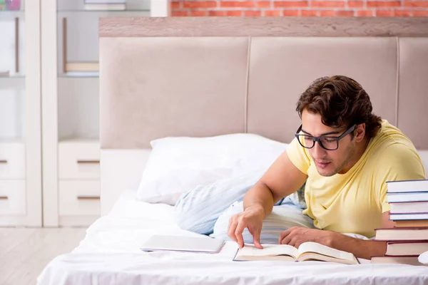 Jovem estudante estudando na cama para exames — Fotografia de Stock