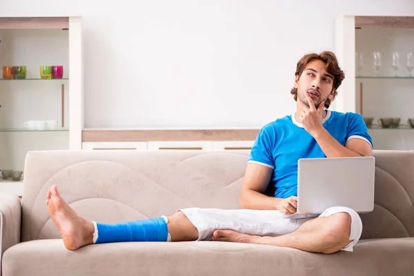 Leg injured young man on the sofa — Stock Photo, Image