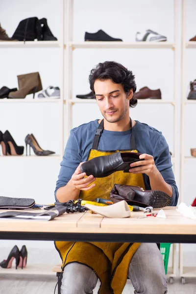 Junger Mann repariert Schuhe in Werkstatt — Stockfoto