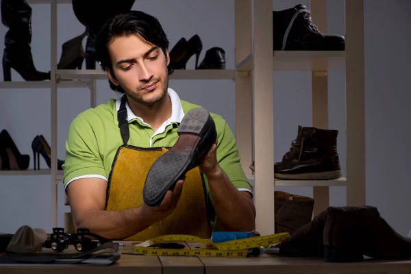 Jonge schoenmaker in workshop bij nacht — Stockfoto