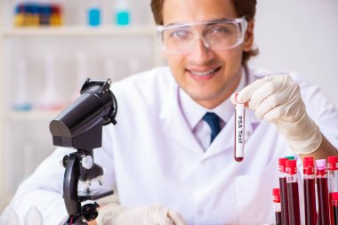 Genç yakışıklı laboratuvar asistanı hastanede kan örnekleri test ediyor. 