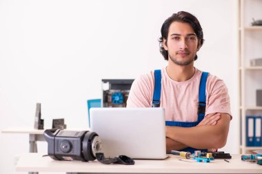 Genç bir erkek müteahhit bilgisayar tamir ediyor.  