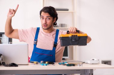 Genç bir erkek müteahhit bilgisayar tamir ediyor.  