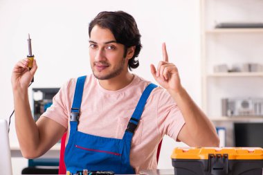 Genç bir erkek müteahhit bilgisayar tamir ediyor.  