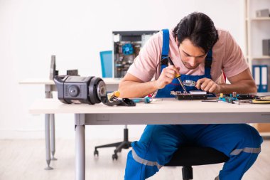 Genç bir erkek müteahhit bilgisayar tamir ediyor.  