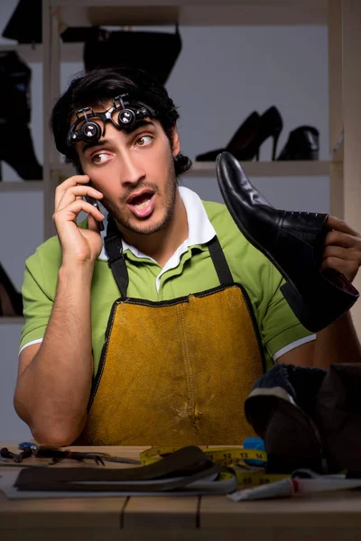 Young shoemaker in workshop at night — Stock Photo, Image