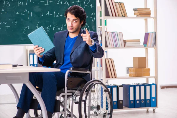 Młody przystojny mężczyzna w wózek inwalidzki przed chalkboard — Zdjęcie stockowe