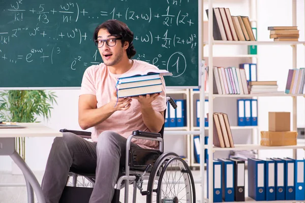 Młody przystojny mężczyzna w wózek inwalidzki przed chalkboard — Zdjęcie stockowe